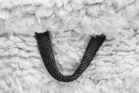 Black fabric hanging loop on white fake fur background closeupの写真素材