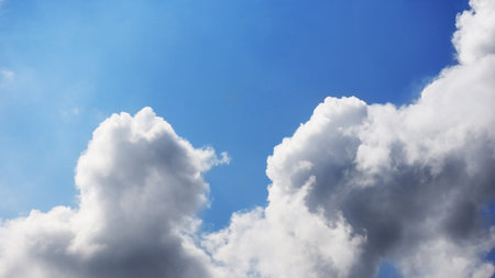 Beautiful white fluffy clouds highlighted by the sun in blue skyの写真素材