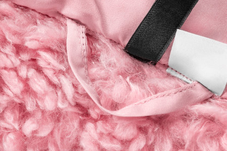 Coat hanging loop stitched on pink teddy fabric background closeupの写真素材