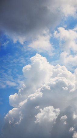 Abstract white and gray cumulus clouds in blue sky highlighted by the sunの写真素材