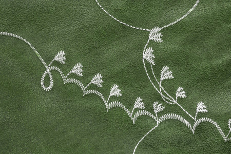 White embroidery on green velvet fabric closeup as a backgroundの写真素材