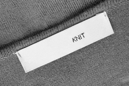 Clothes label text knit on gray kit wool fabric background closeup