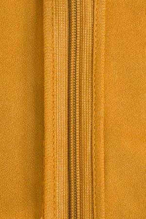 Yellow clothes zip in yellow fabric closeup as a backgroundの写真素材