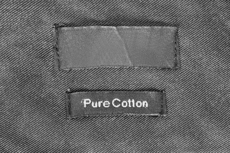 Clothes label text pure cotton stitched on black fabric backgroundの写真素材
