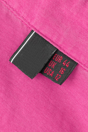 Size 44 clothes label over fuchsia pink color fabric backgroundの写真素材