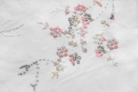 Floral pattern silk embroidery on white canvas closeup as a backgroundの写真素材