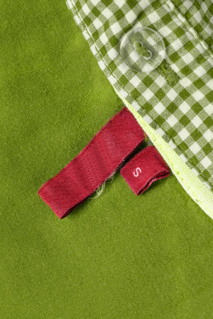 Size S red clothes label over green cotton fabric background
