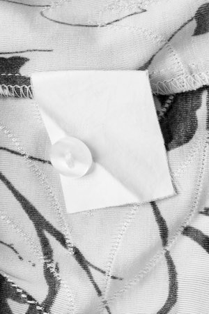 Blank clothes label with a button over white and black back side fabricの写真素材