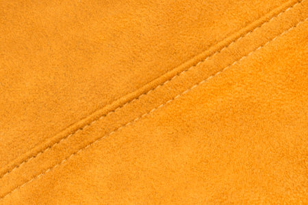 Yellow velvet fabric stitched seam closeup as a backgroundの写真素材