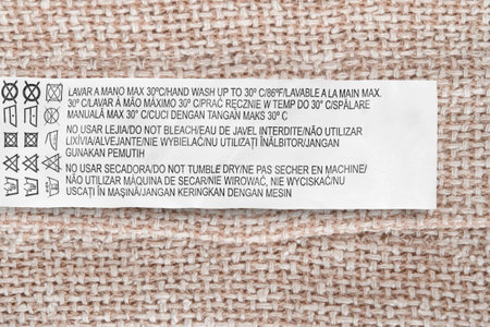 Care instructions clothes label in different languages over canvas fabric background closeup