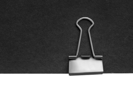 Binder clip on black blank paper sheet closeup as a backgroundの写真素材