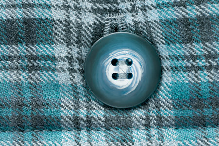 Coat button sewn on blue tartan wool fabric background closeupの写真素材