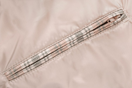 Zipped clothes pocket in beige fabric closeup as a background