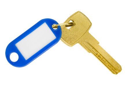 Golden door key with blank plastic tag trinket isolated on white backgroundの写真素材