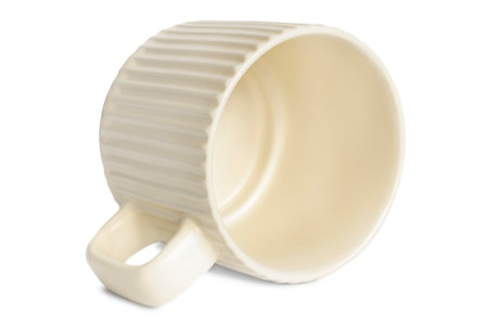 Empty ribbed ceramic beige cup lying on white backgroundの写真素材