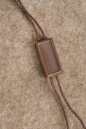 Blank plastic tag over beige wool fabric background closeup