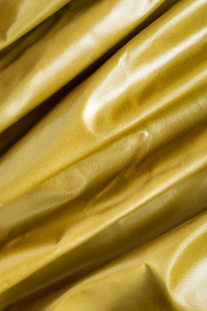 Golden color draped latex fabric closeup as a backgroundの写真素材