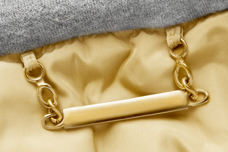 Blank golden clothes nameplate hanging on chains over fabric background closeupの写真素材