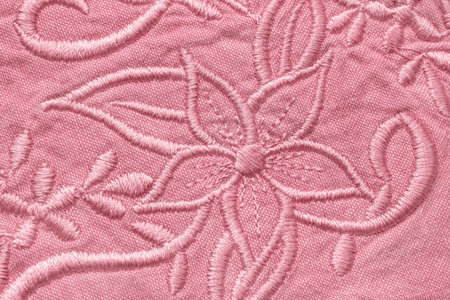 Pastel pink floral embroidery on cotton fabric closeup as a backgroundの写真素材
