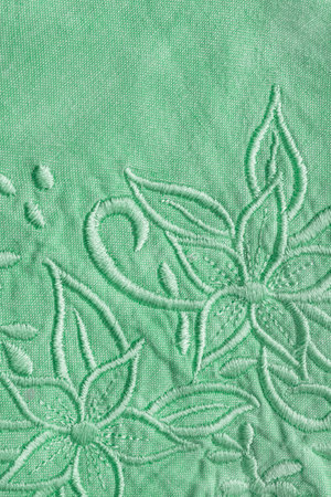 Embroidered floral pattern on pastel green cotton fabric closeup as a backgroundの写真素材