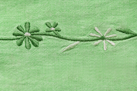 Embroidered flowers on green canvas fabric closeup as a backgroundの写真素材