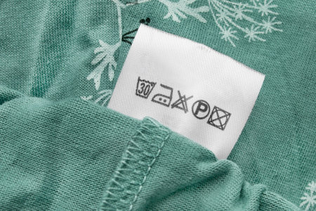 Care instructions clothes label on green fabric background closeupの写真素材