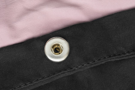 Clothes snap button on black and pink fabric closeup as a background