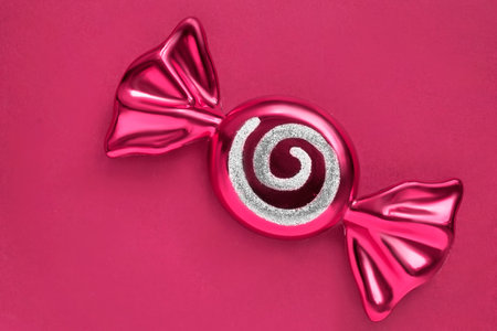 Pink glass candy shaped christmas bauble over pink studio backgroundの写真素材