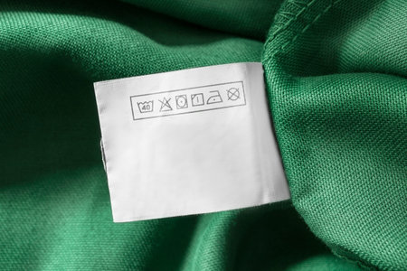 Care instructions clothes label on green fabric background