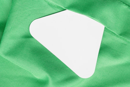 Blank triangle price tag clothes label over green linen fabric backgroundの写真素材