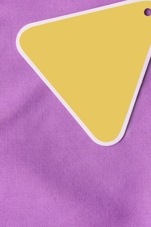 Blank yellow price tag label over purple fabric background closeupの写真素材