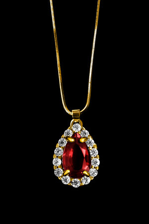 Elegant ruby and diamonds pendant hanging on chain isolated over blackの写真素材