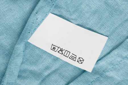 Washing instructions clothes label over light blue cotton fabric backgroundの写真素材