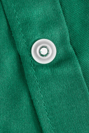 White plastic snap button on green fabric background closeupの写真素材