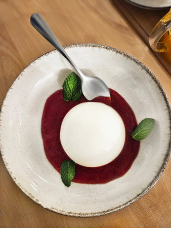 Panna cotta italian dessert with jam and mint on a plate on a table