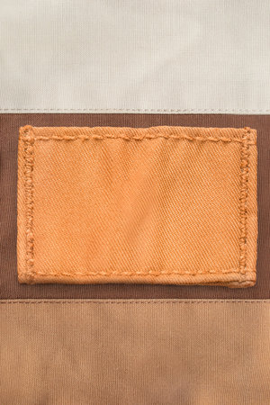 Blank yellow fabric patch stitched on cotton fabric background closeup