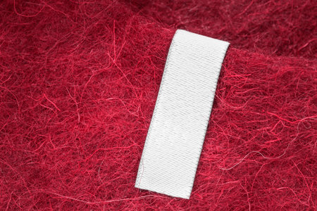 Blank white clothes label on red felt wool background closeupの写真素材