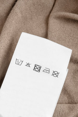 Care instructions clothes label over beige knit wool fabric background closeupの写真素材