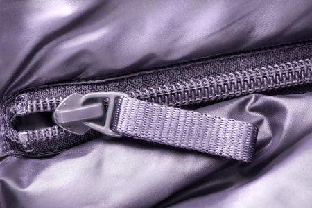 Purple plastic zipper in purple fabric closeup as a background