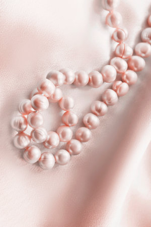 Pink pearl necklace lying on pastel satin fabric backgroundの写真素材