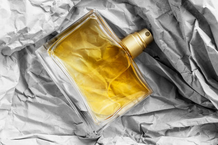 Yellow perfume glass bottle lying on crumpled craft packaging paper backgroundの写真素材