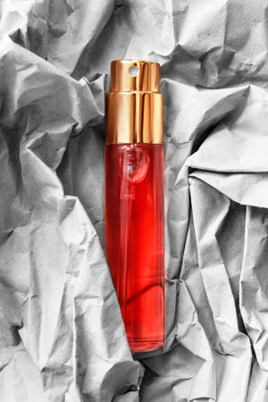 Red perfume glass atomizer over white crumpled packaging paper as a backgroundの写真素材