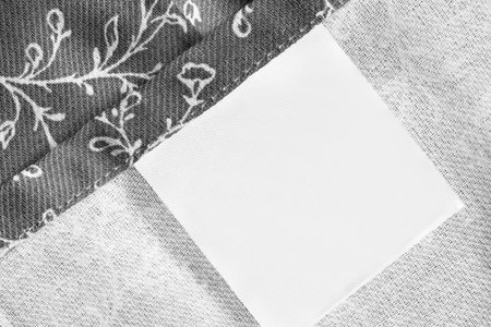 Blank clothes label on grey fabric underside closeup as a background