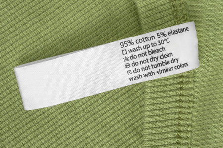 Fabric composition and care instructions label over green knit fabric background