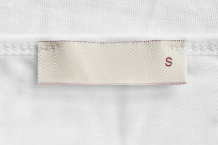 Size S clothes label on white knit fabric background closeup