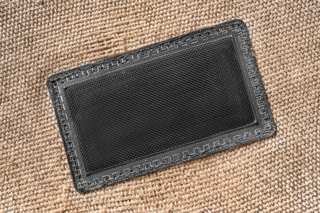 Blank netting patch label stitched on beige canvas fabric background