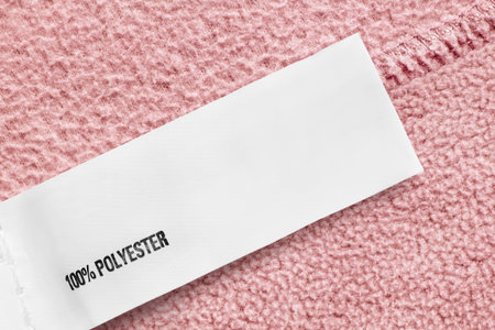 100% polyester clothes label over pastel pink fleece fabric background