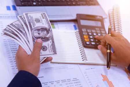 Businessman's hands with calculator at the office and Financial data analyzing counting on desk in office.の写真素材