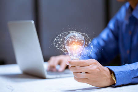 Business hand holding light bulb,with brain icon,creativity and innovative are keys to success,new ideas and innovation concept.の写真素材