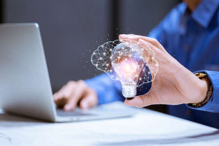 Business hand holding light bulb,with brain icon,creativity and innovative are keys to success,new ideas and innovation concept.の写真素材
